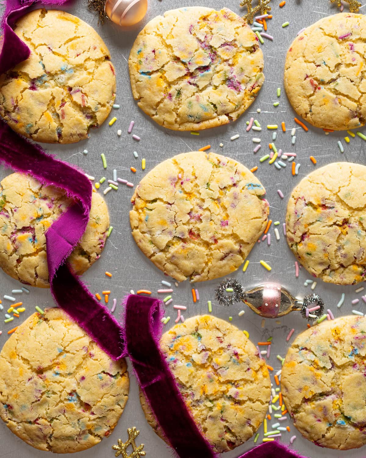 Soft Oversized Crinkled Sprinkle Sugar Cookies on a baking sheet with a purple ribbon.