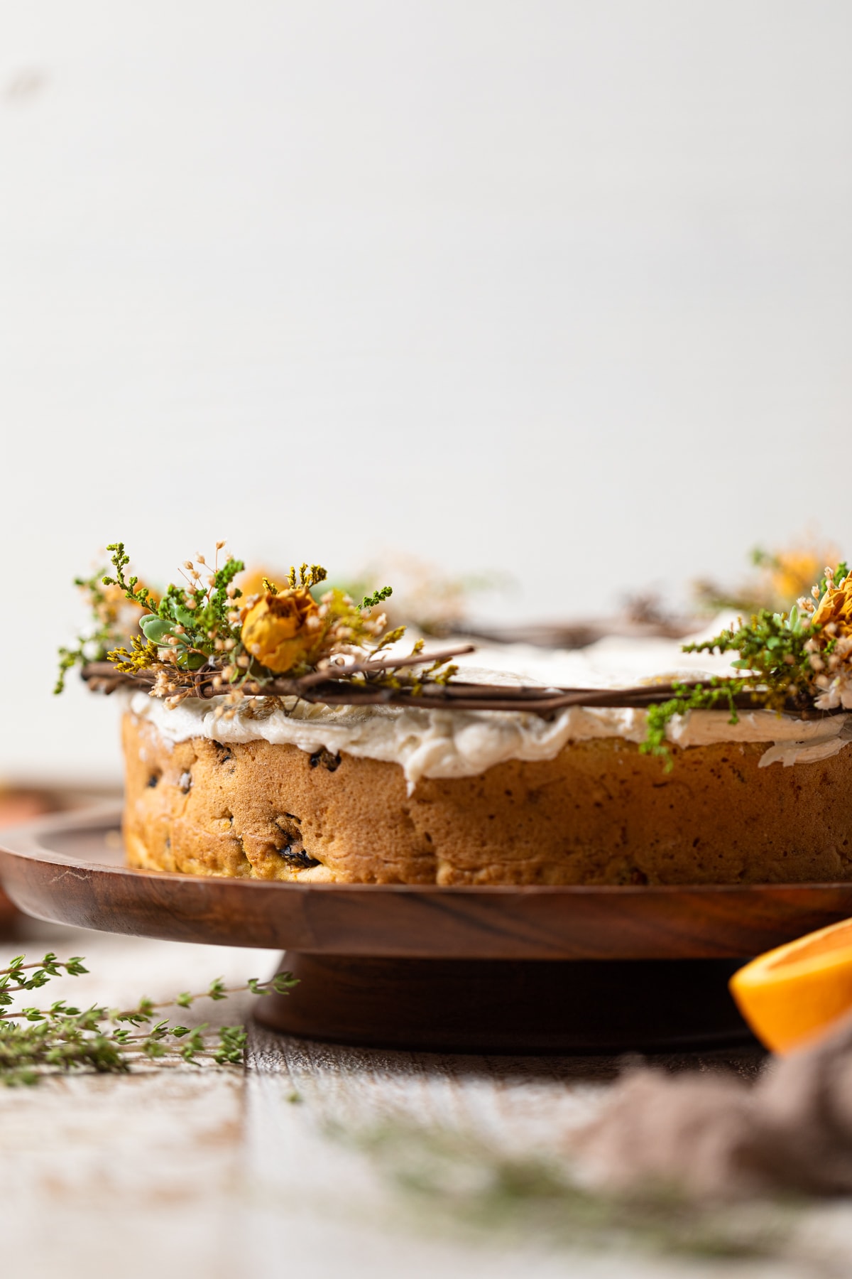 Side view of a Vegan Carrot Cake with Orange-infused Frosting on a wooden platter