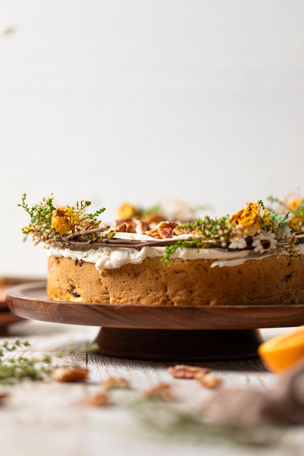 Side view of a Vegan Carrot Cake with Orange-infused Frosting on a wooden platter