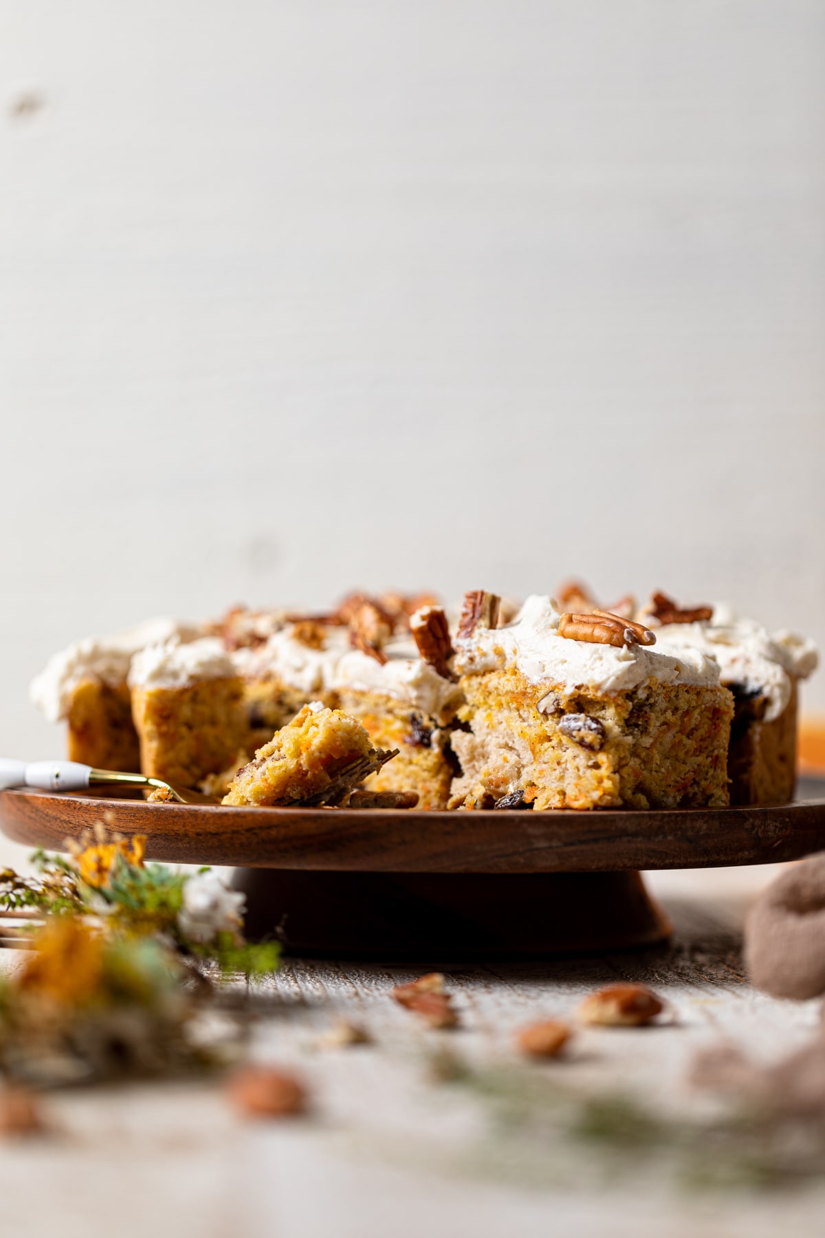 Sliced Vegan Carrot Cake with Orange-infused Frosting on a wooden platter