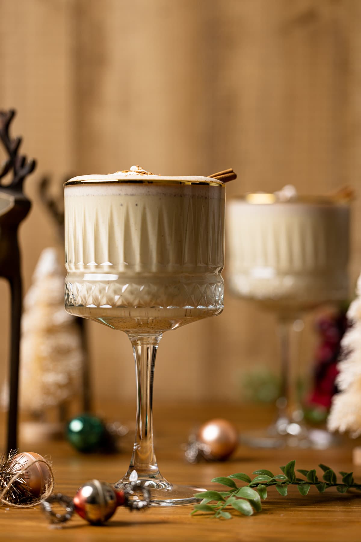 Two long-stemmed, gold-rimmed glasses of Creamy Homemade Vegan Eggnog.