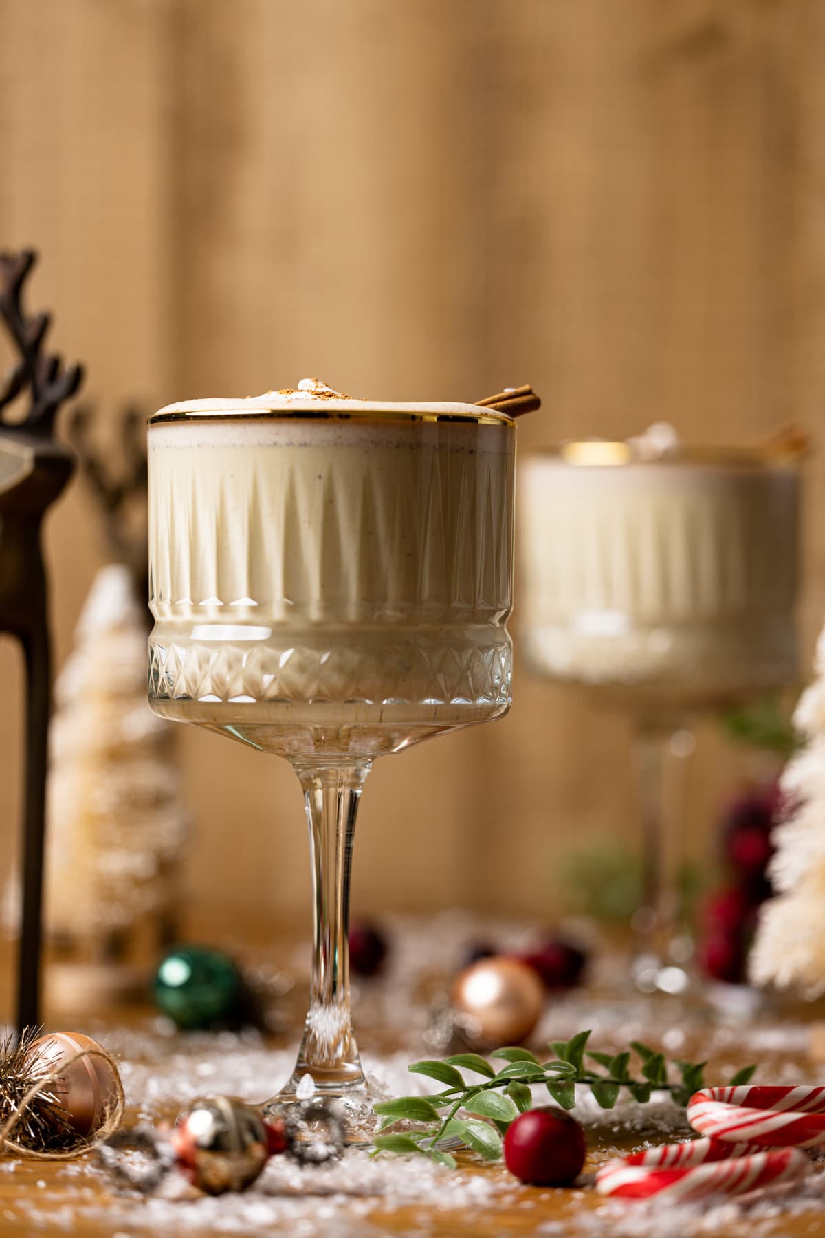 Two long-stemmed, gold-rimmed glasses of Creamy Homemade Vegan Eggnog.