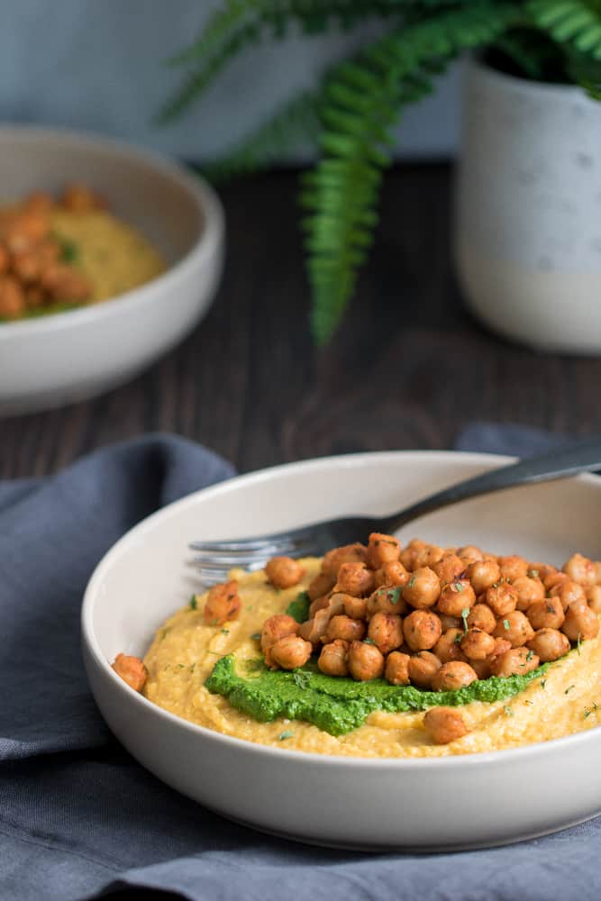 Vegan \'Cheese\' Polenta and Kale Pesto with Roasted Chickpea in a white bowl.