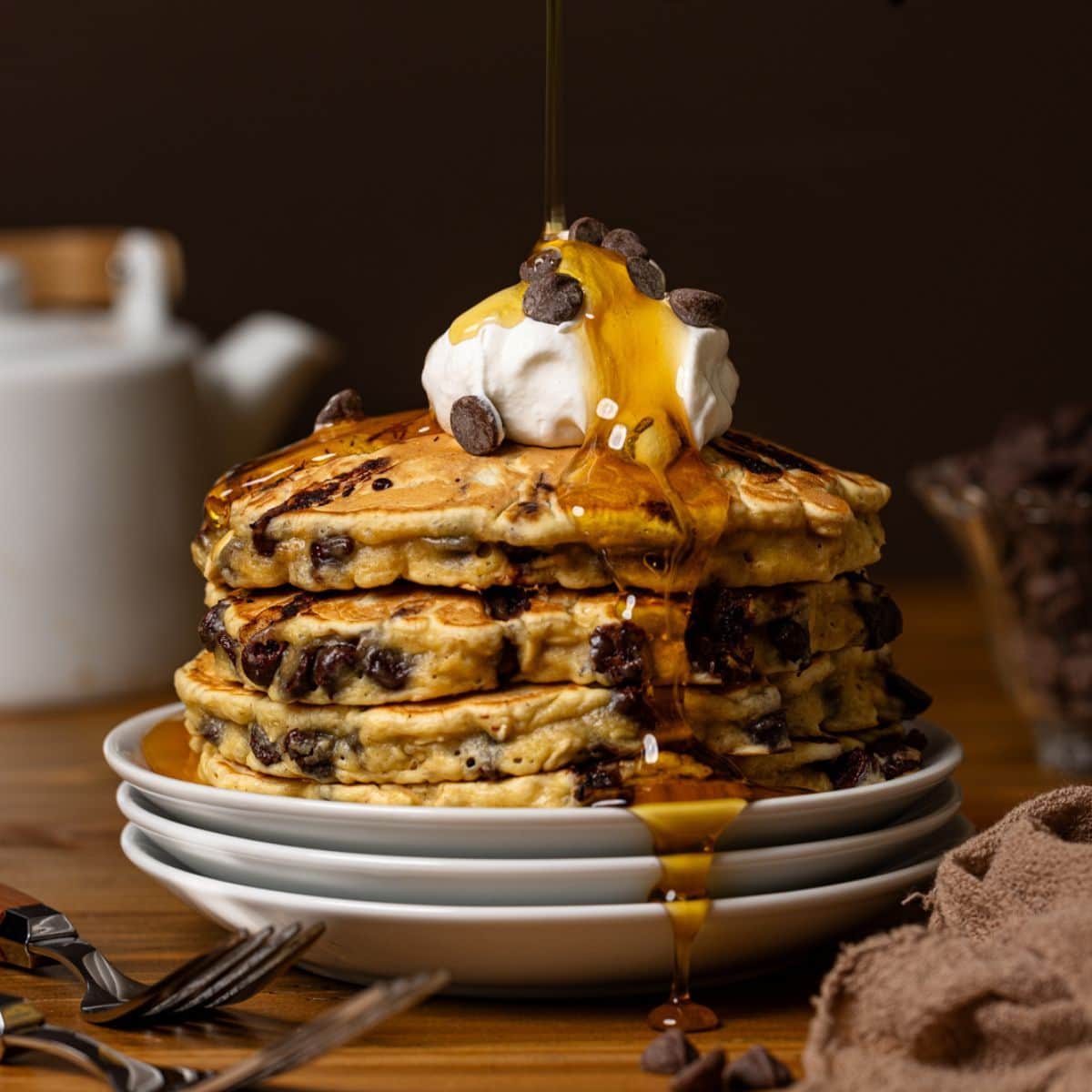 Syrup being poured atop a stack of pancakes.