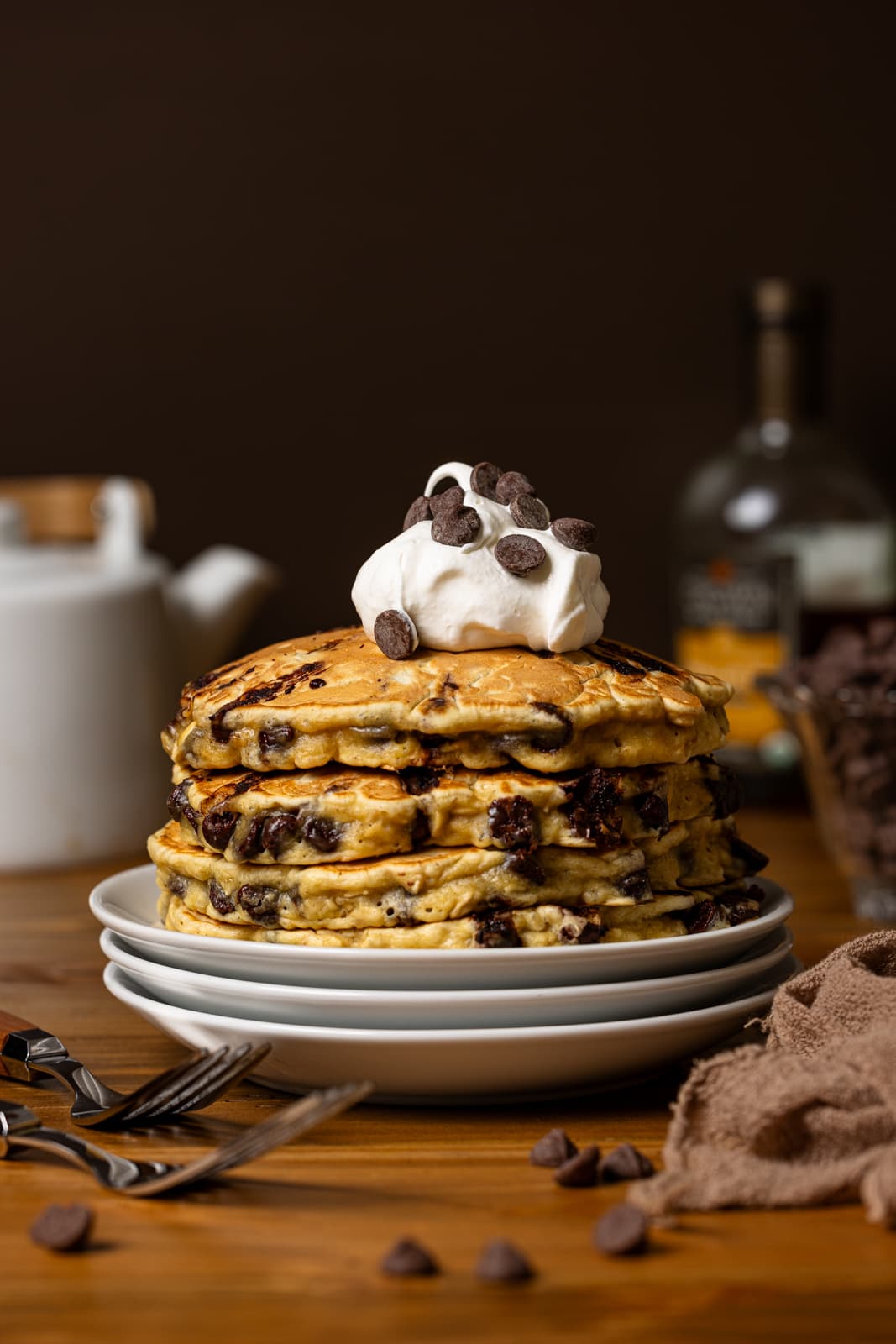 Chocolate chip pancakes with whipped cream and forks.