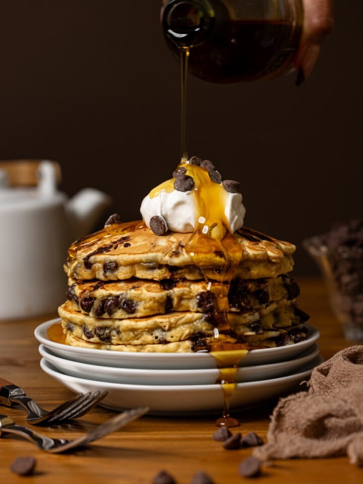 Syrup being poured atop a stack of pancakes.