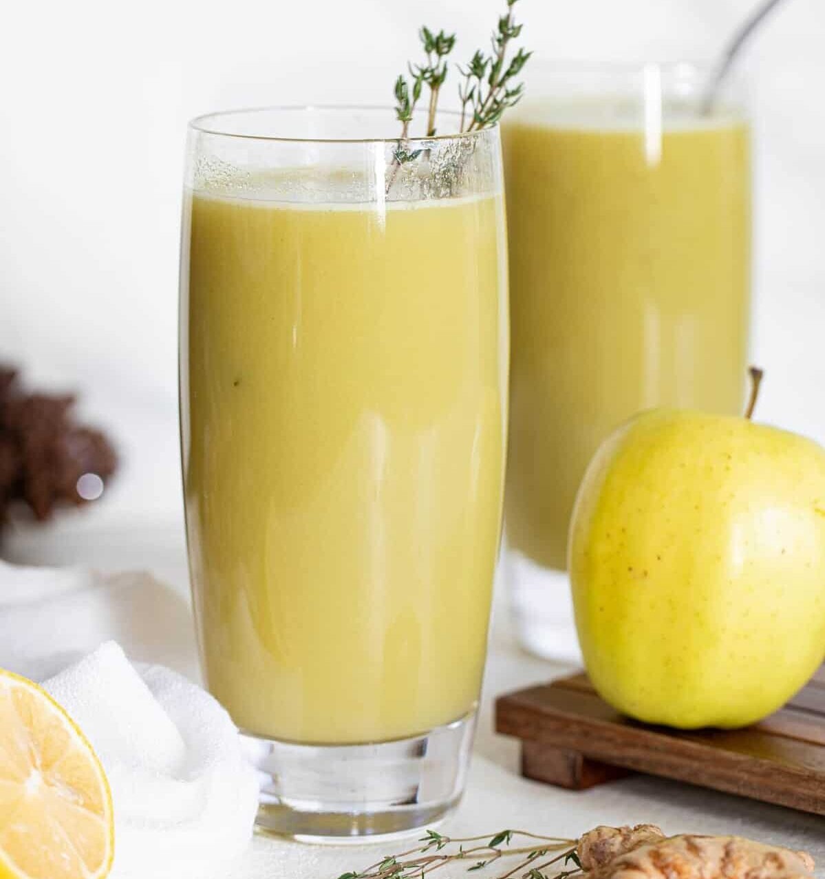 Apple next to a glass of Cucumber Ginger Lemon Detox Juice.