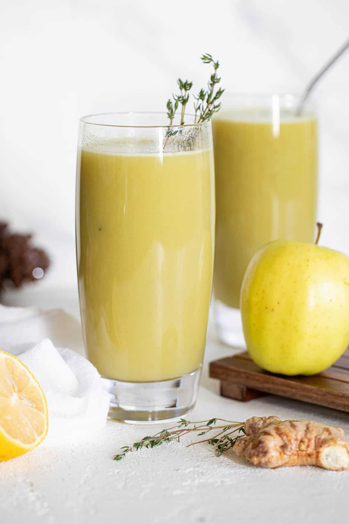 Apple next to a glass of Cucumber Ginger Lemon Detox Juice.