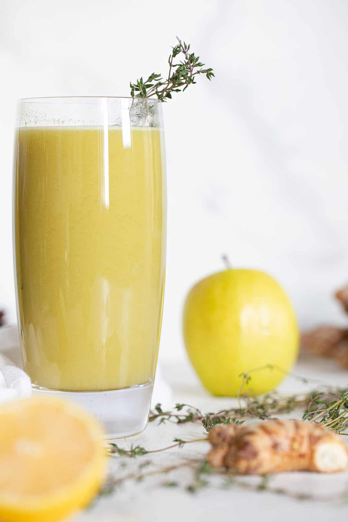 Cucumber Ginger Lemon Detox Juice near ginger, thyme, and an apple.