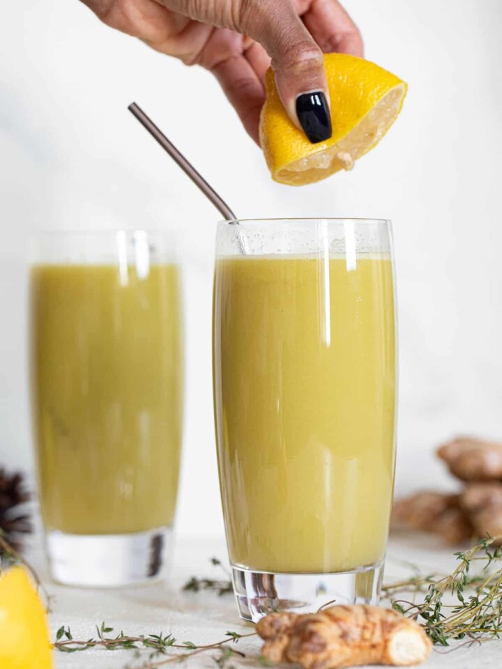 Woman squeezing a lemon into a Cucumber Ginger Lemon Detox Juice.