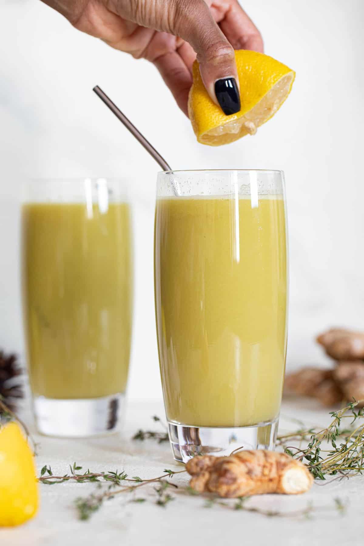 Woman squeezing a lemon into a Cucumber Ginger Lemon Detox Juice.