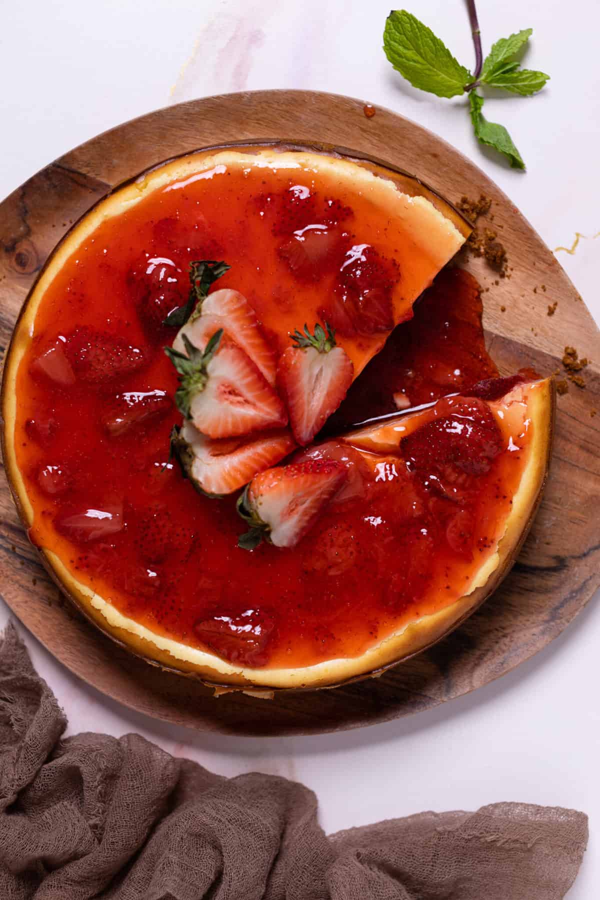 New York-Style Cheesecake topped with strawberries and strawberry sauce.