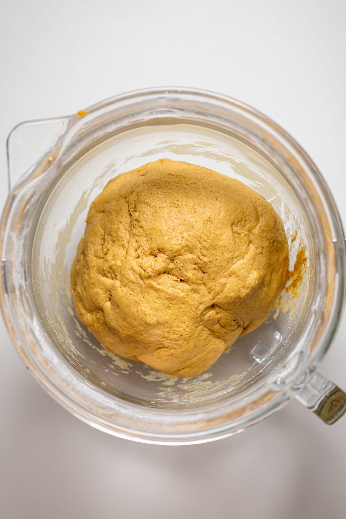 Ball of Vegan Sweet Potato Cinnamon Roll dough in a glass bowl