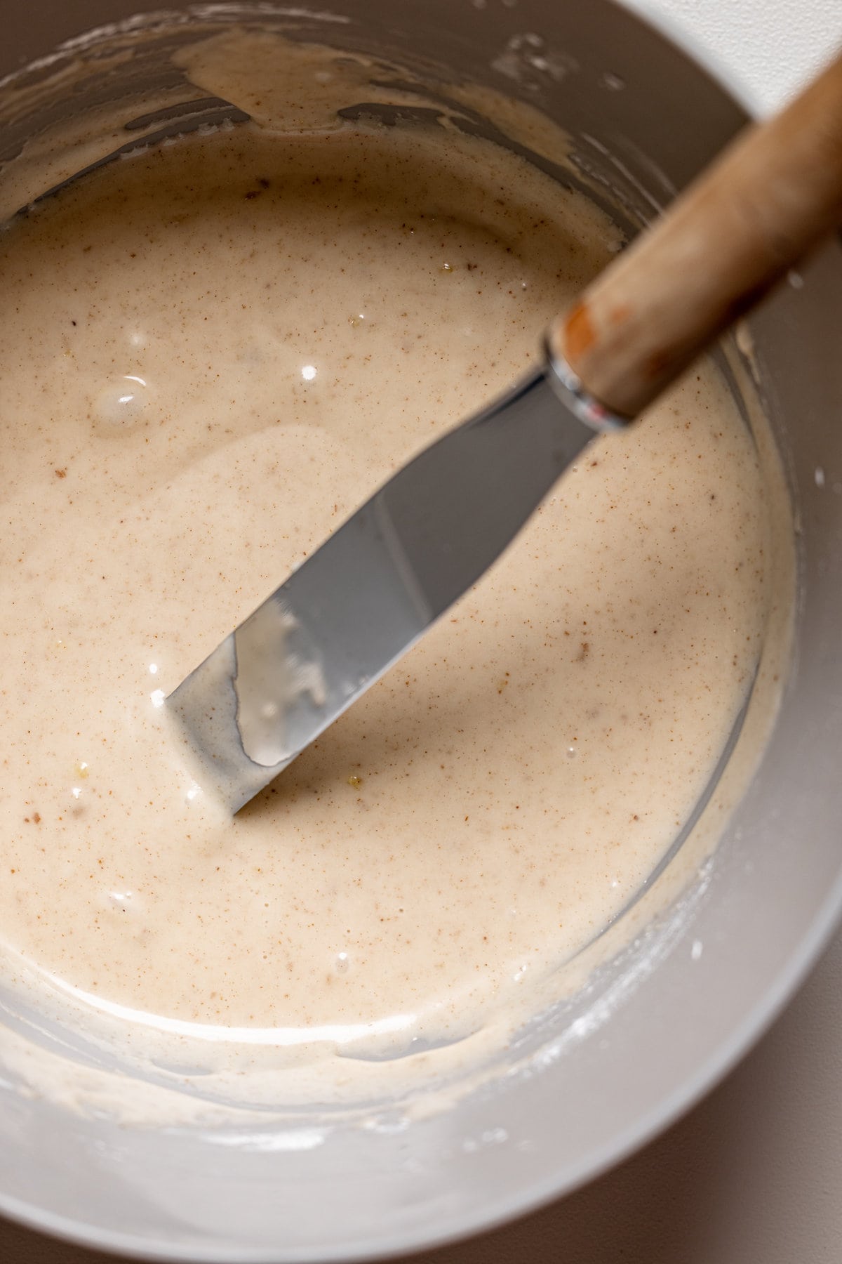 Icing knife sticking out of a bowl of glaze