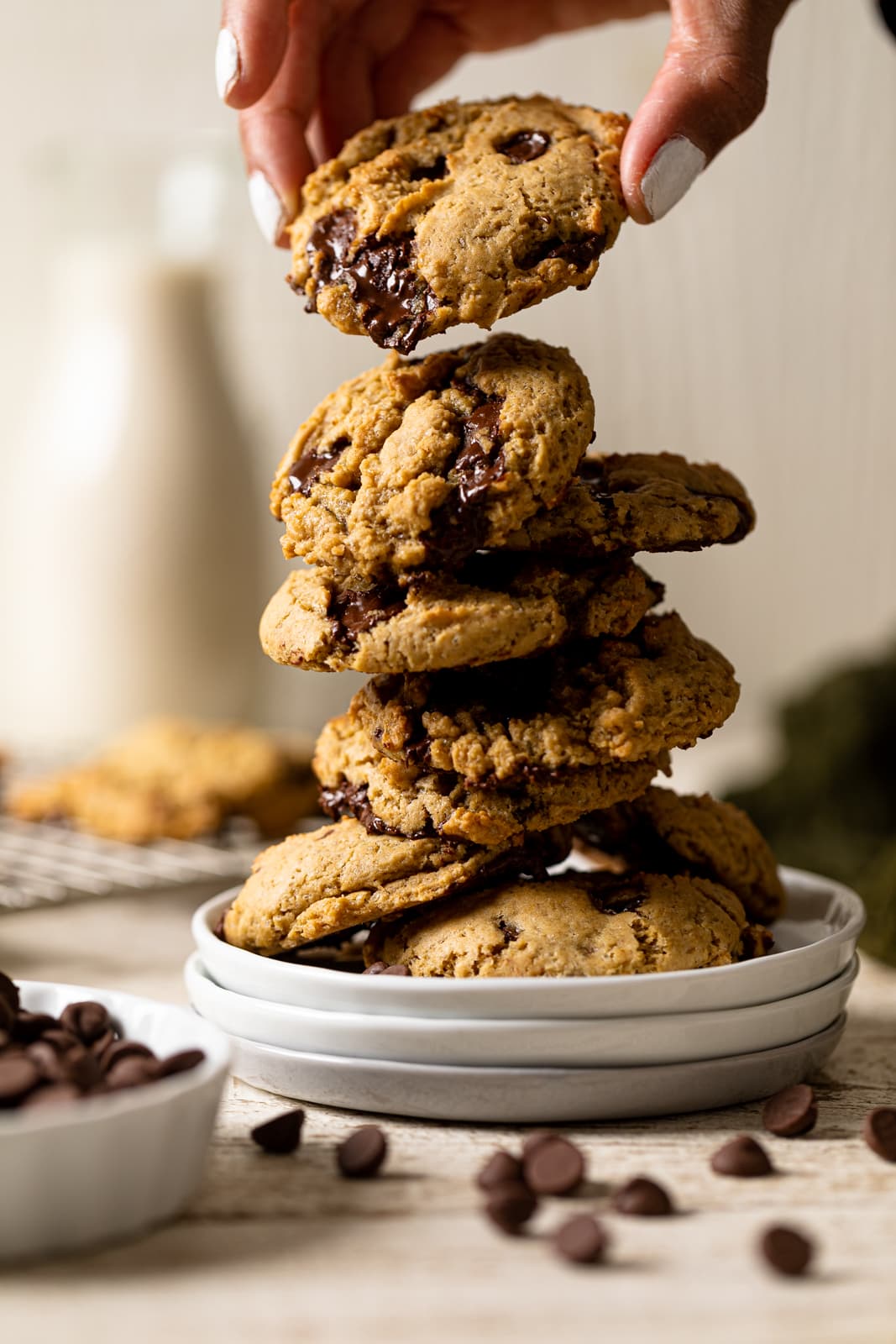 Hand grabbing a Vegan Chocolate Chip Cookie from a tall stack