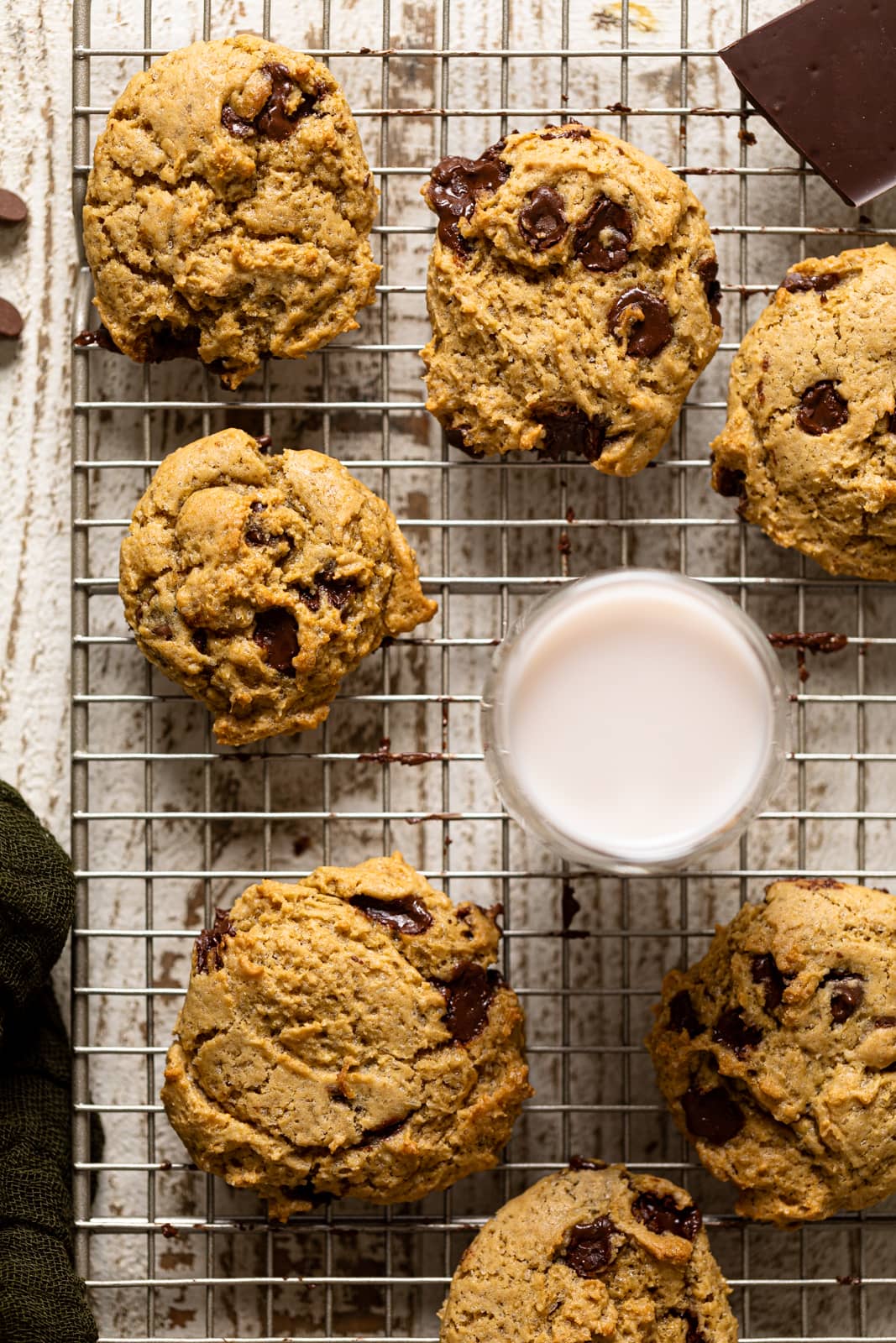 Vegan Chocolate Chip Cookies and a glass of dairy-free milk on a wire rack