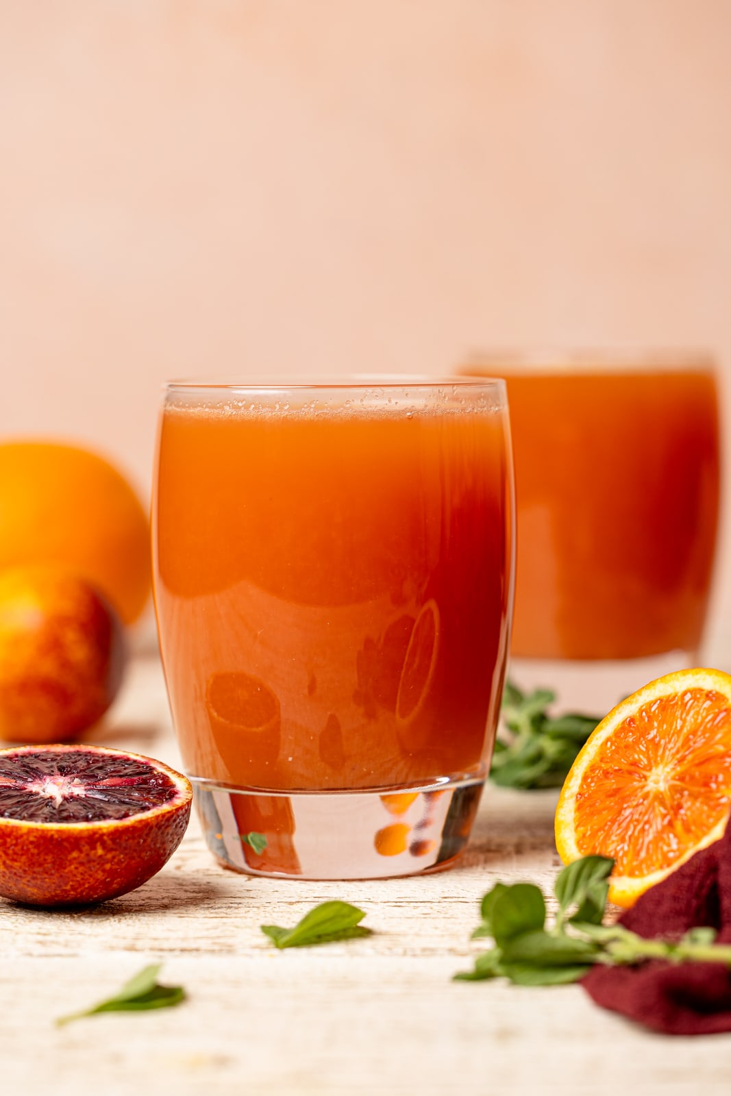 Juice in two glasses on a white wood table with blood oranges.
