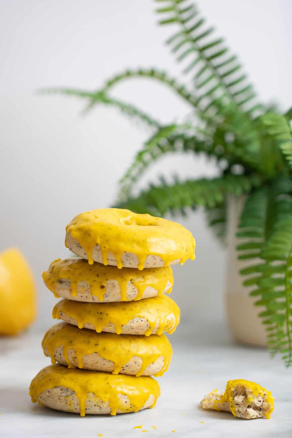 Vegan Lemon Poppy Seed Donuts stacked on a countertop.