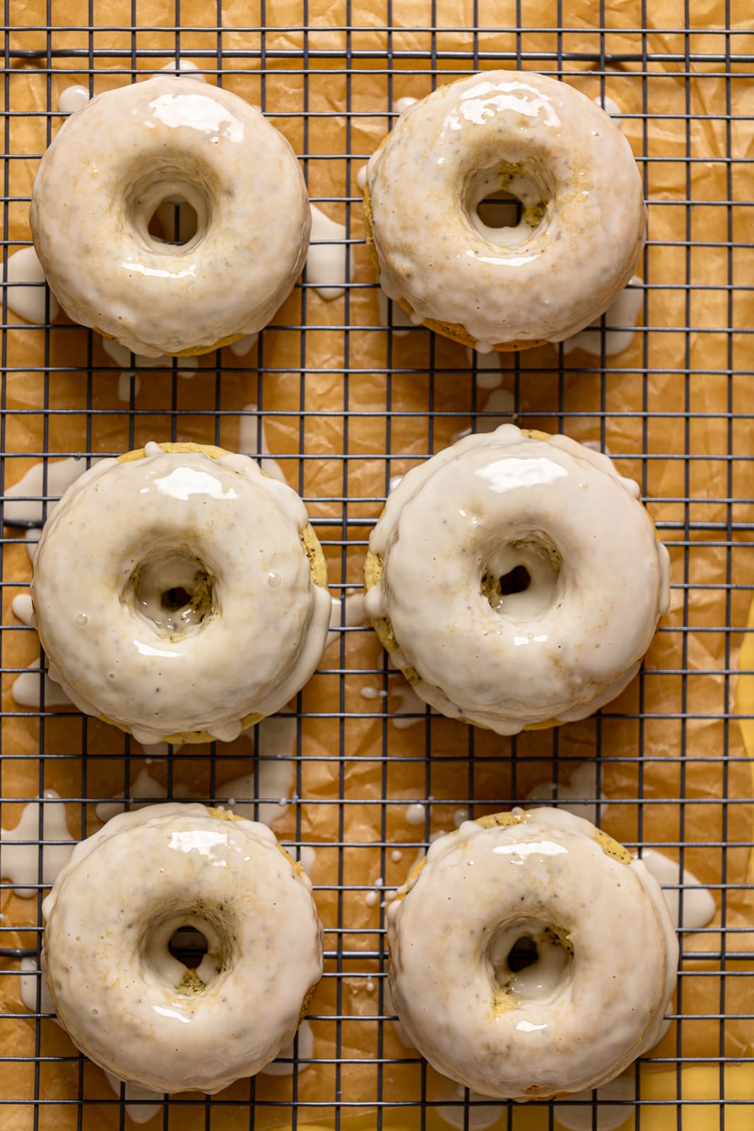 Freshly glazed Vegan Lemon Poppy Seed Donuts on a wire rack