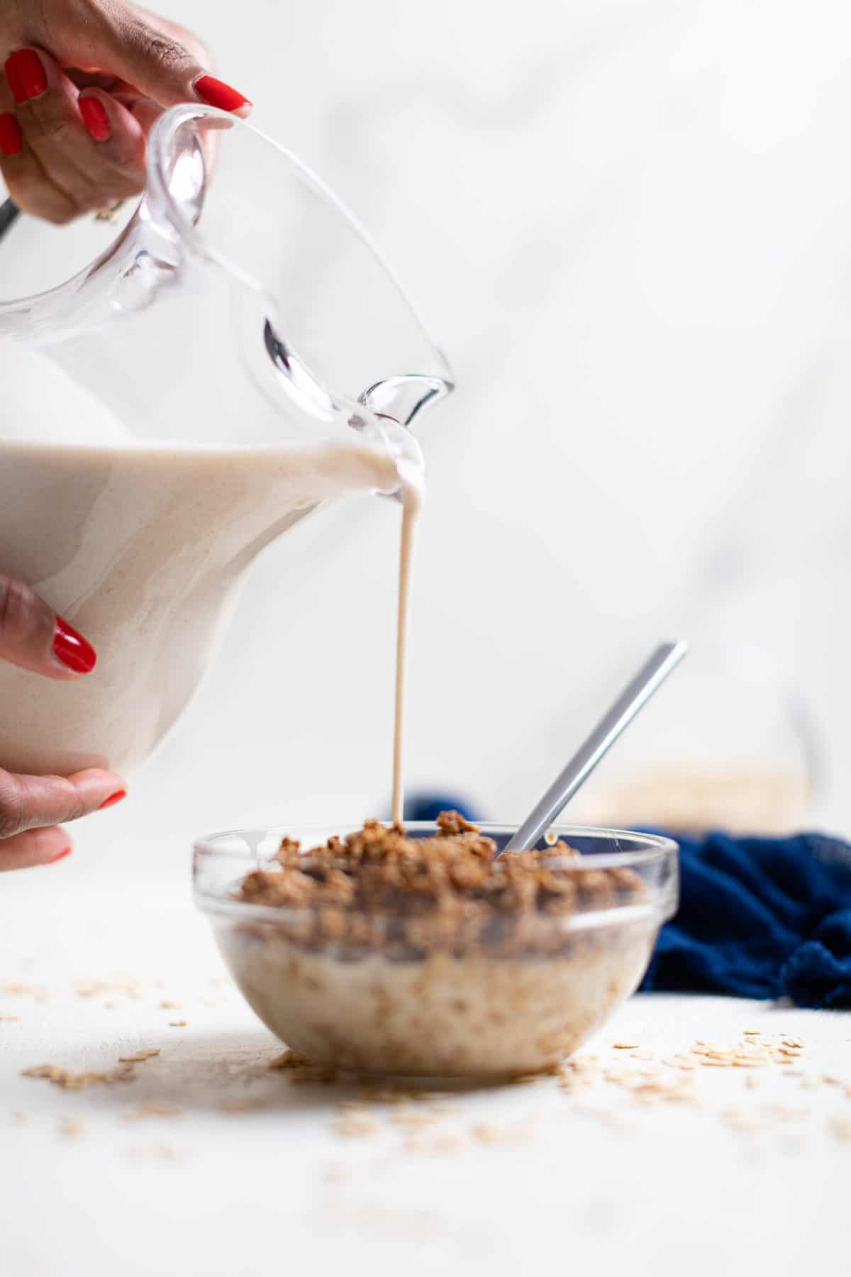 Glass pictures pouring Oat Milk into a bowl.