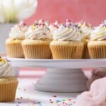 Vanilla Cupcakes with Buttercream Frosting topped with sprinkles on an elevated platter.