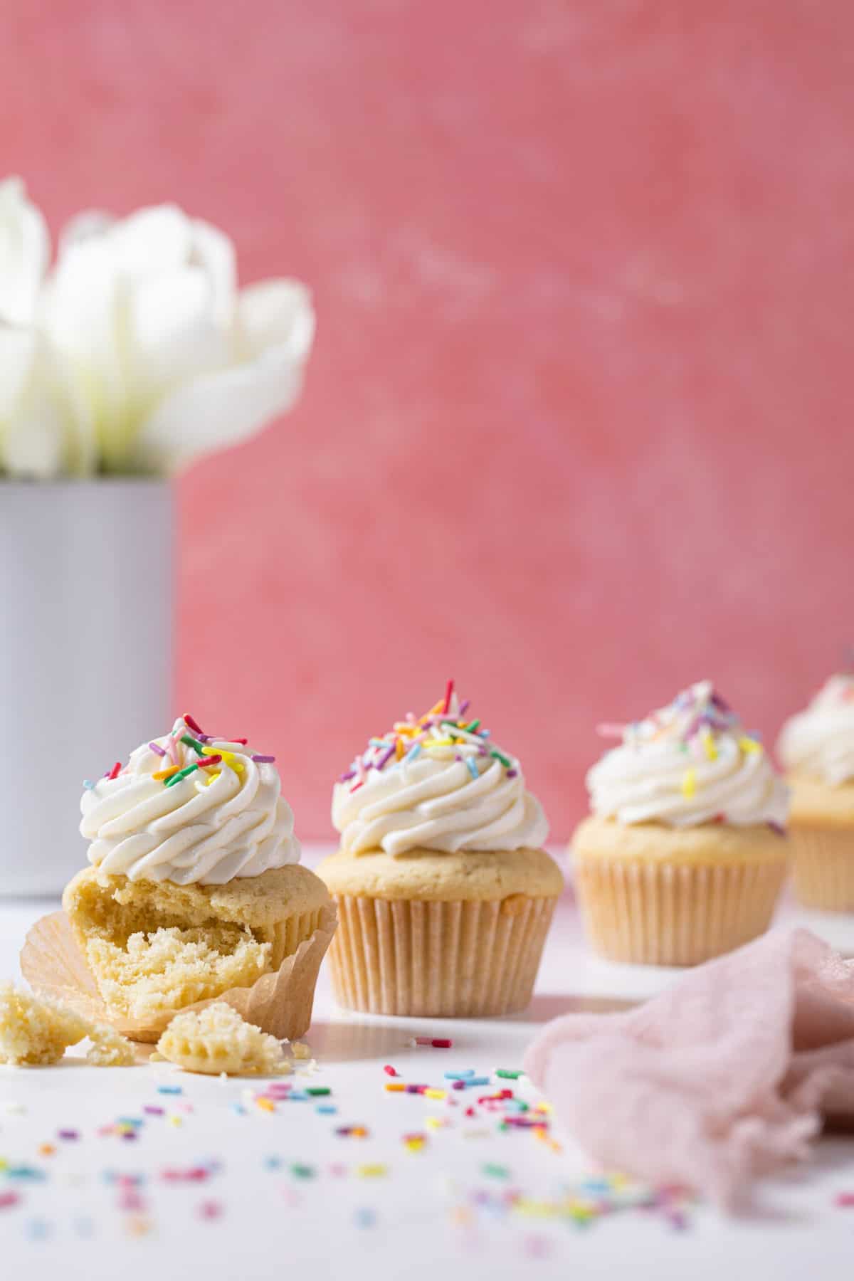 Line of Vanilla Cupcakes with Buttercream Frosting, on of which is missing a bite.