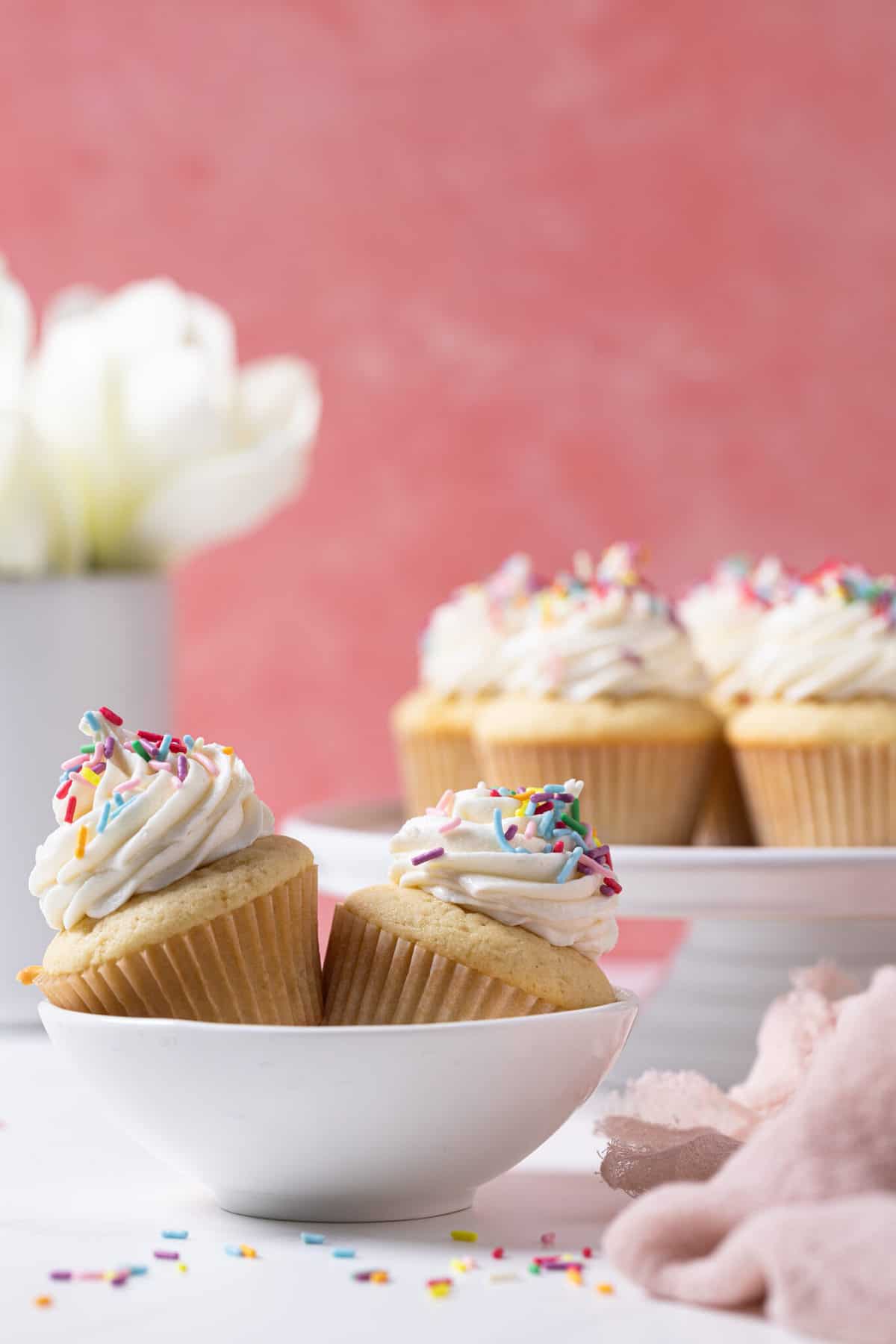 Two Vanilla Cupcakes with Buttercream Frosting in a small bowl.