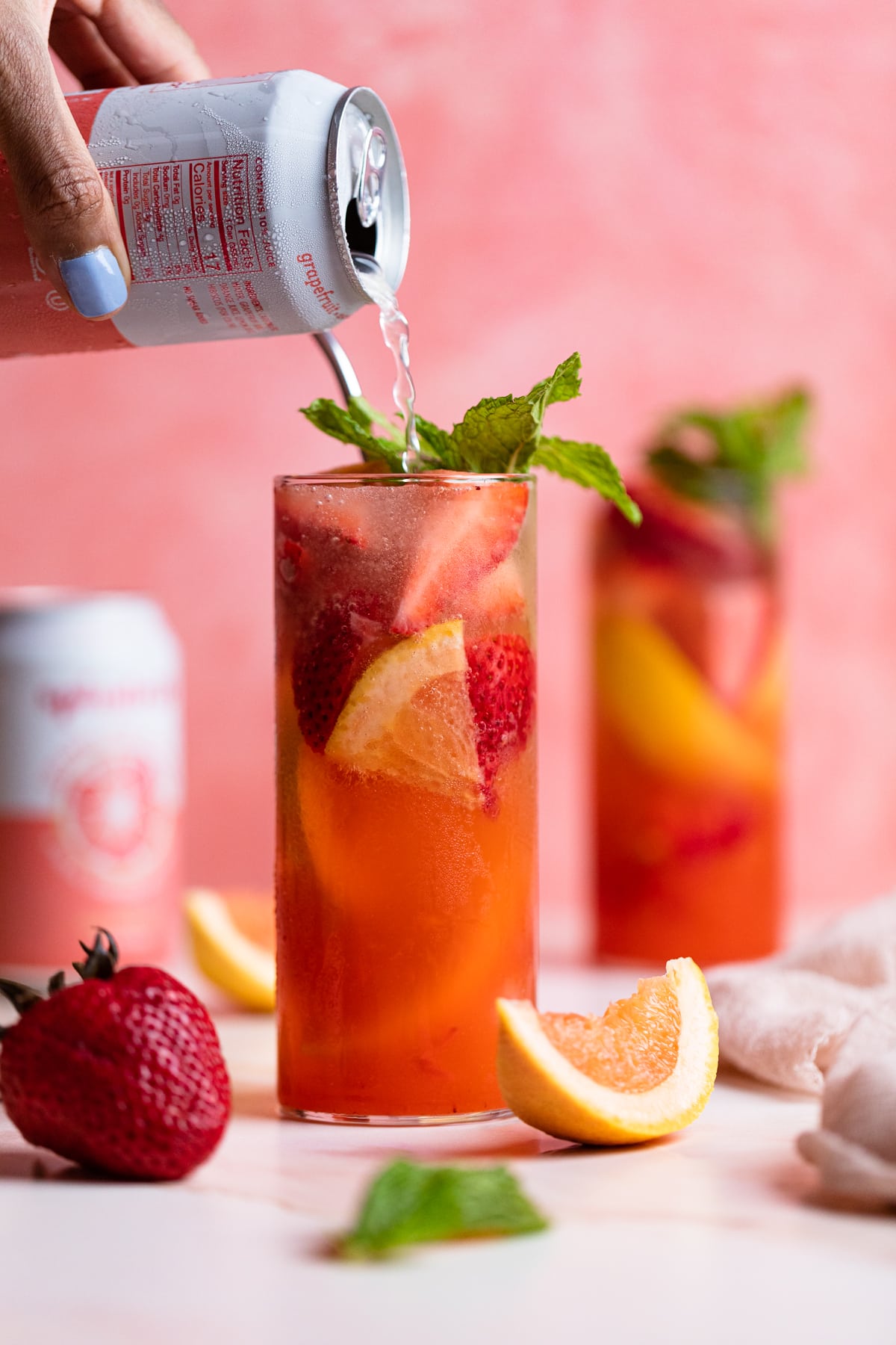 Person pouring soda into a glass of Strawberry Grapefruit Mint Spring Soda.