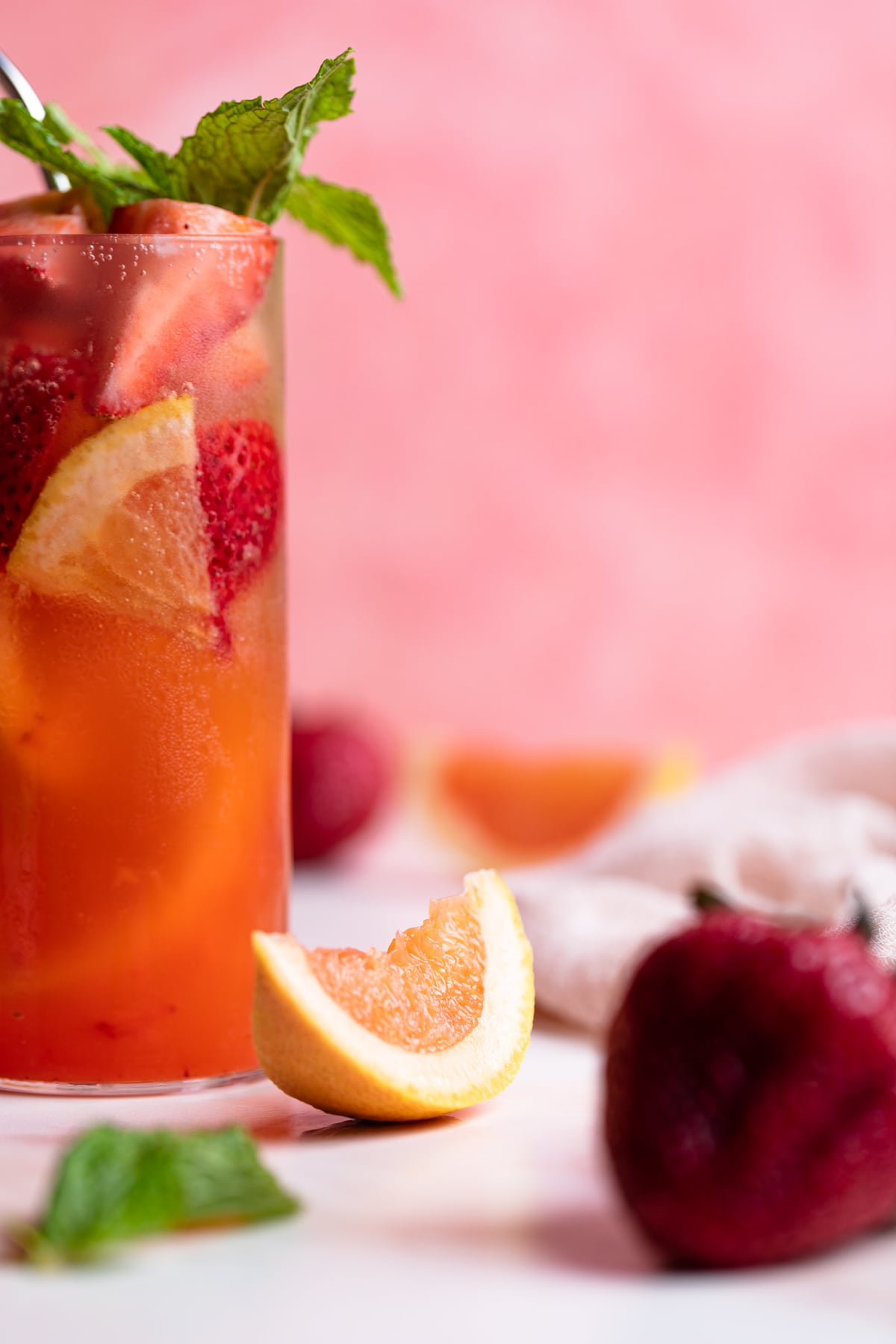 Grapefruits and strawberries on a table with Strawberry Grapefruit Mint Spring Sodas.