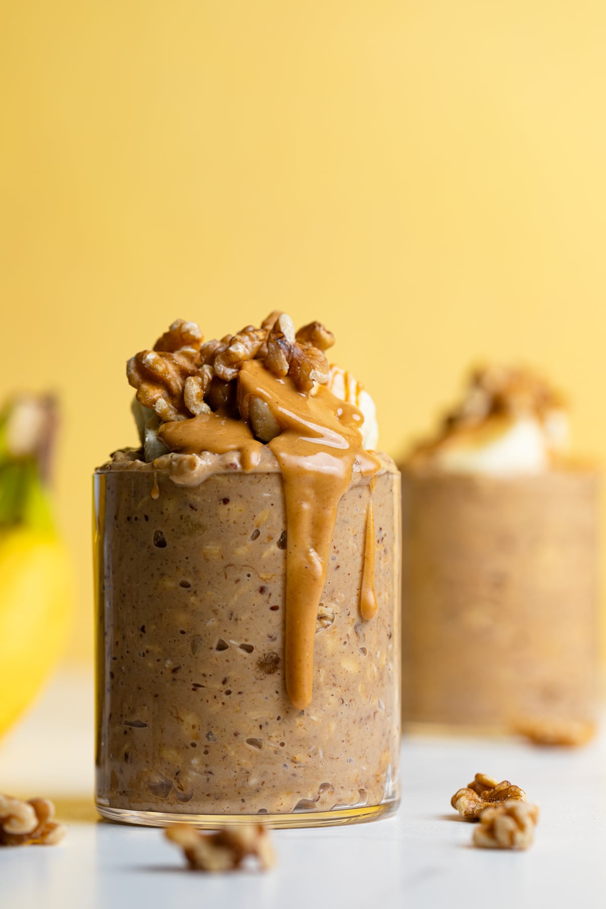 Glass of Banana Peanut Butter Overnight Oats dripping with peanut butter.