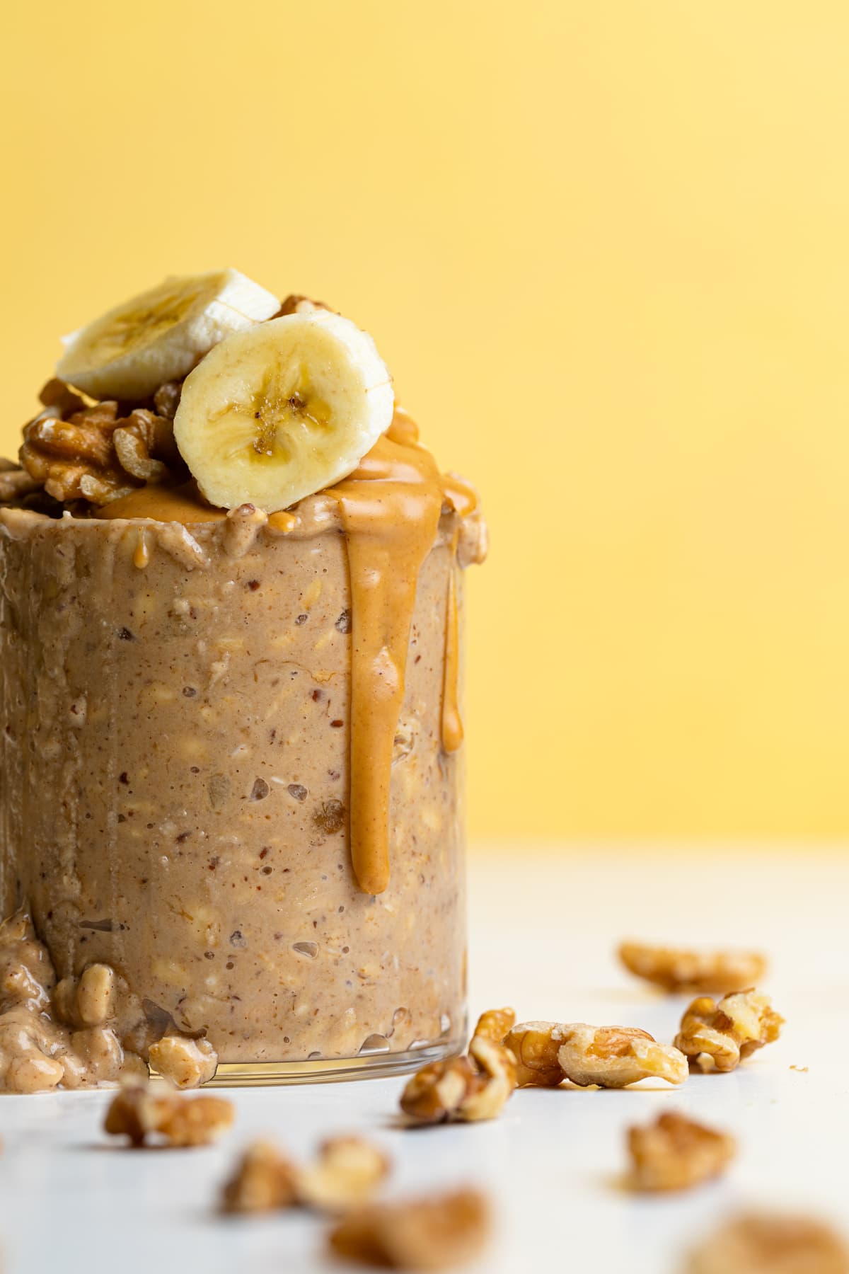 Peanut butter dripping down the side of a glass of Banana Peanut Butter Overnight Oats.