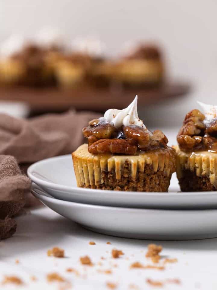 Two Pecan Pie Cheesecake Bites on two small, stacked plates.