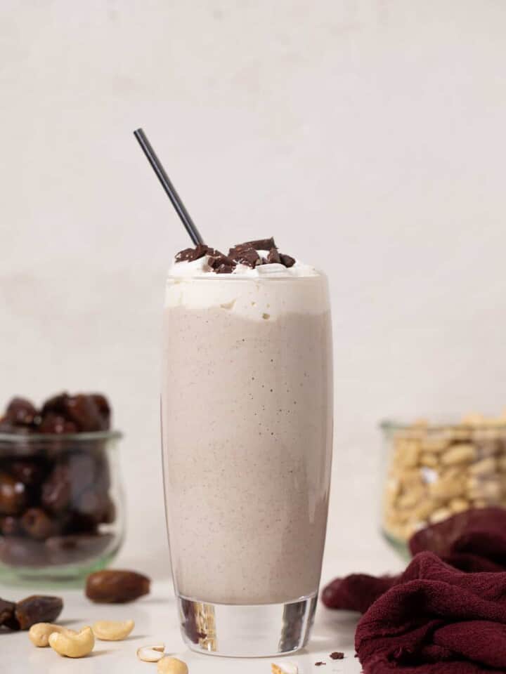 Straw in a tall glass of Cashew Date Morning Shake.