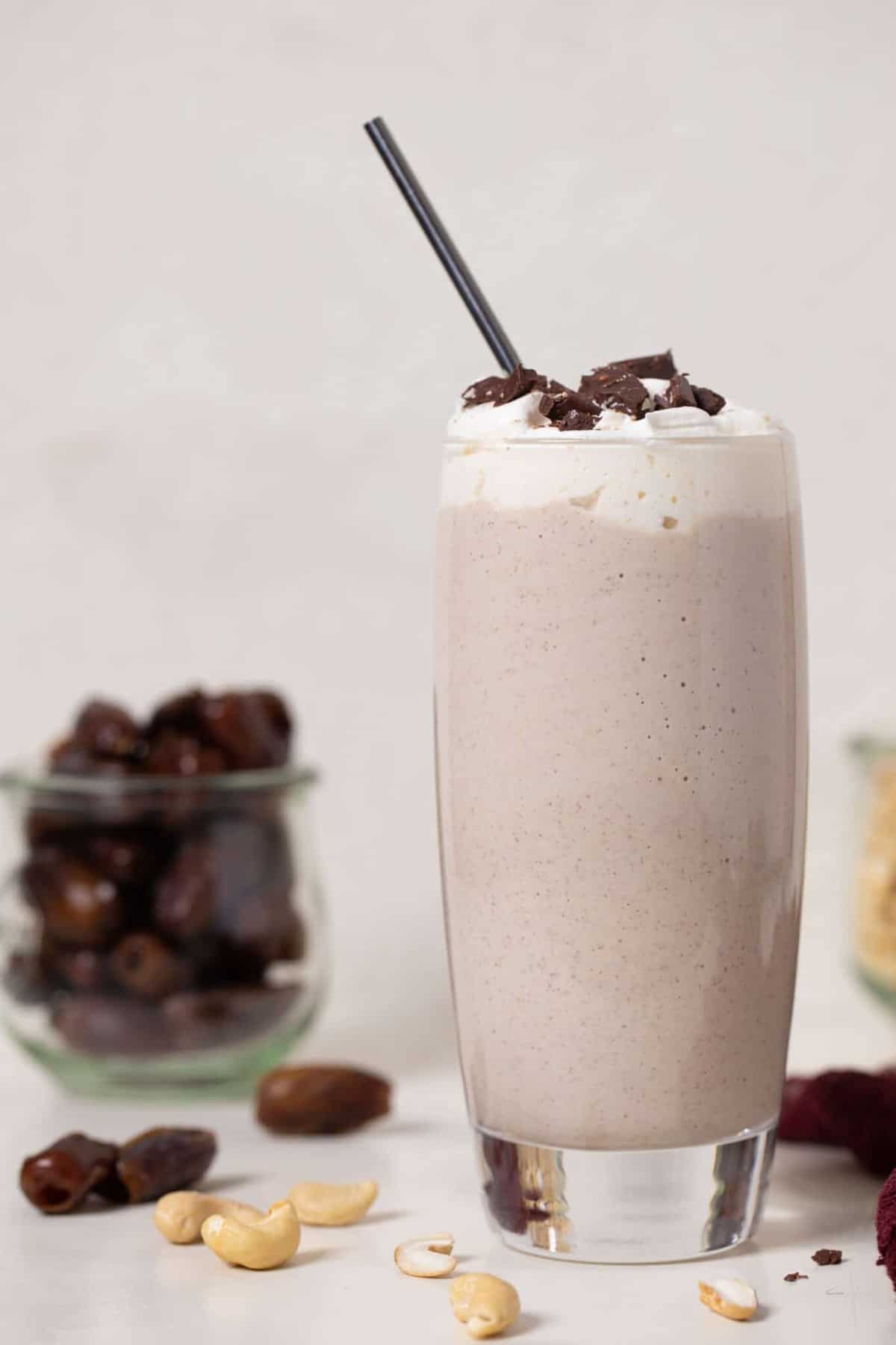 Cashew Date Morning Shake on a table with cashews and dates.