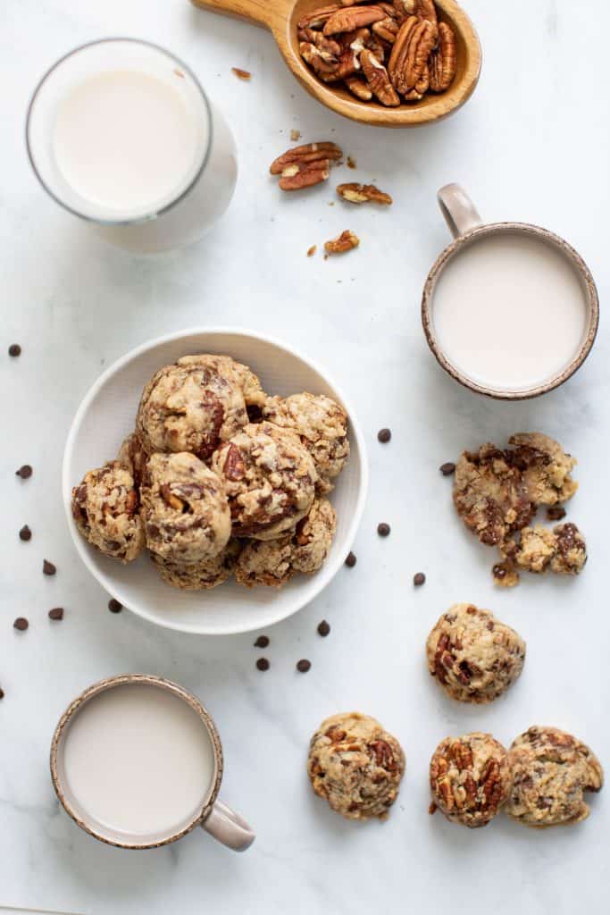 Dairy-Free Chocolate Chip Pecan Cookies in and around a bowl on a marble countertop.