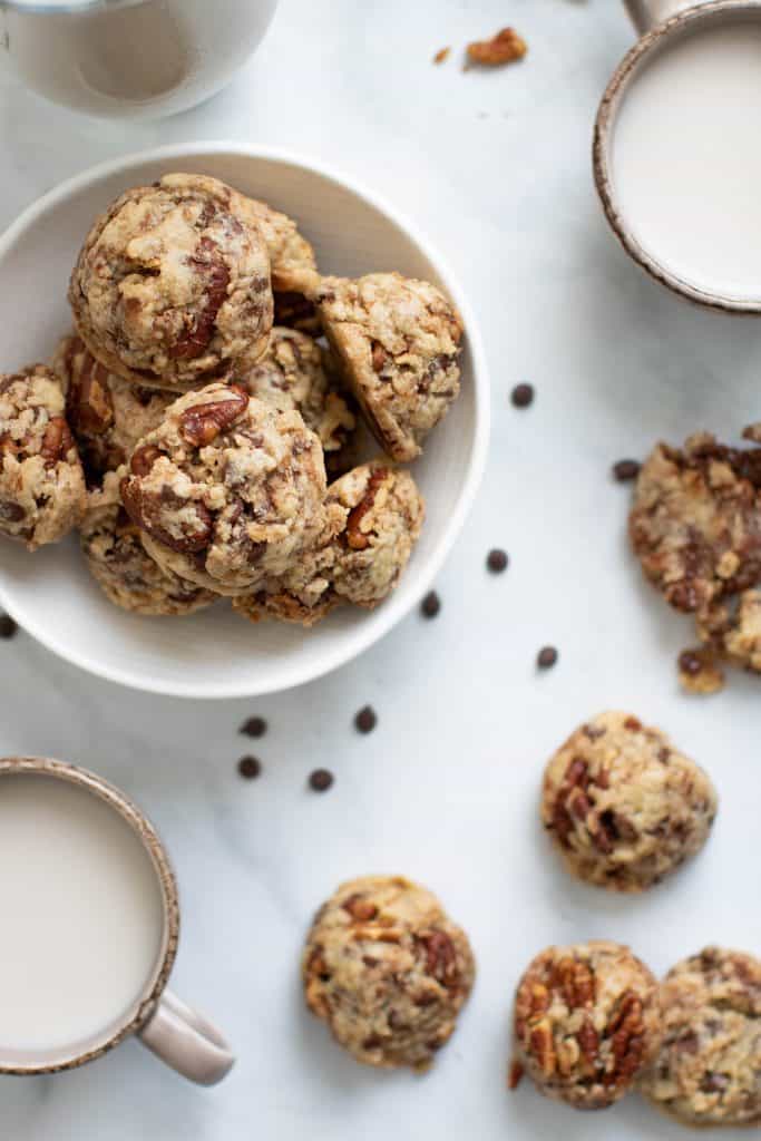 Dairy-Free Chocolate Chip Pecan Cookies in a bowl and on a counter top with chocolate chips.