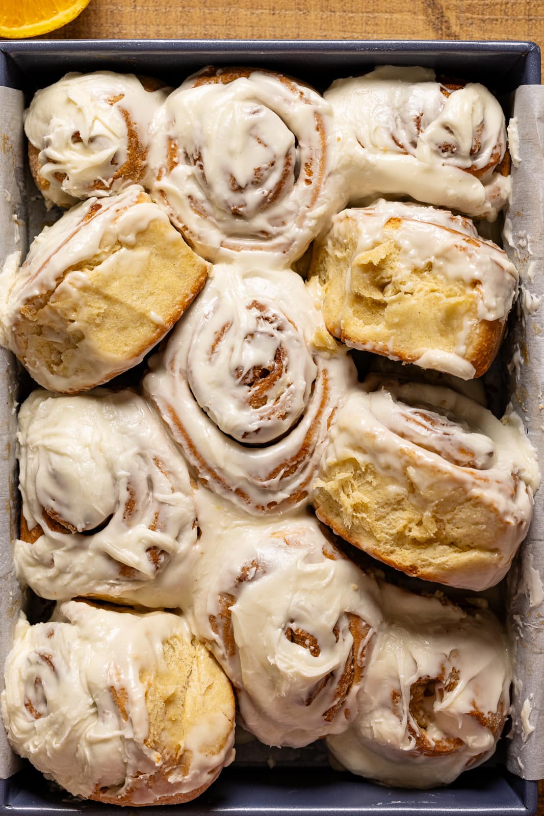 Cinnamon rolls in a baking dish with some turned over.