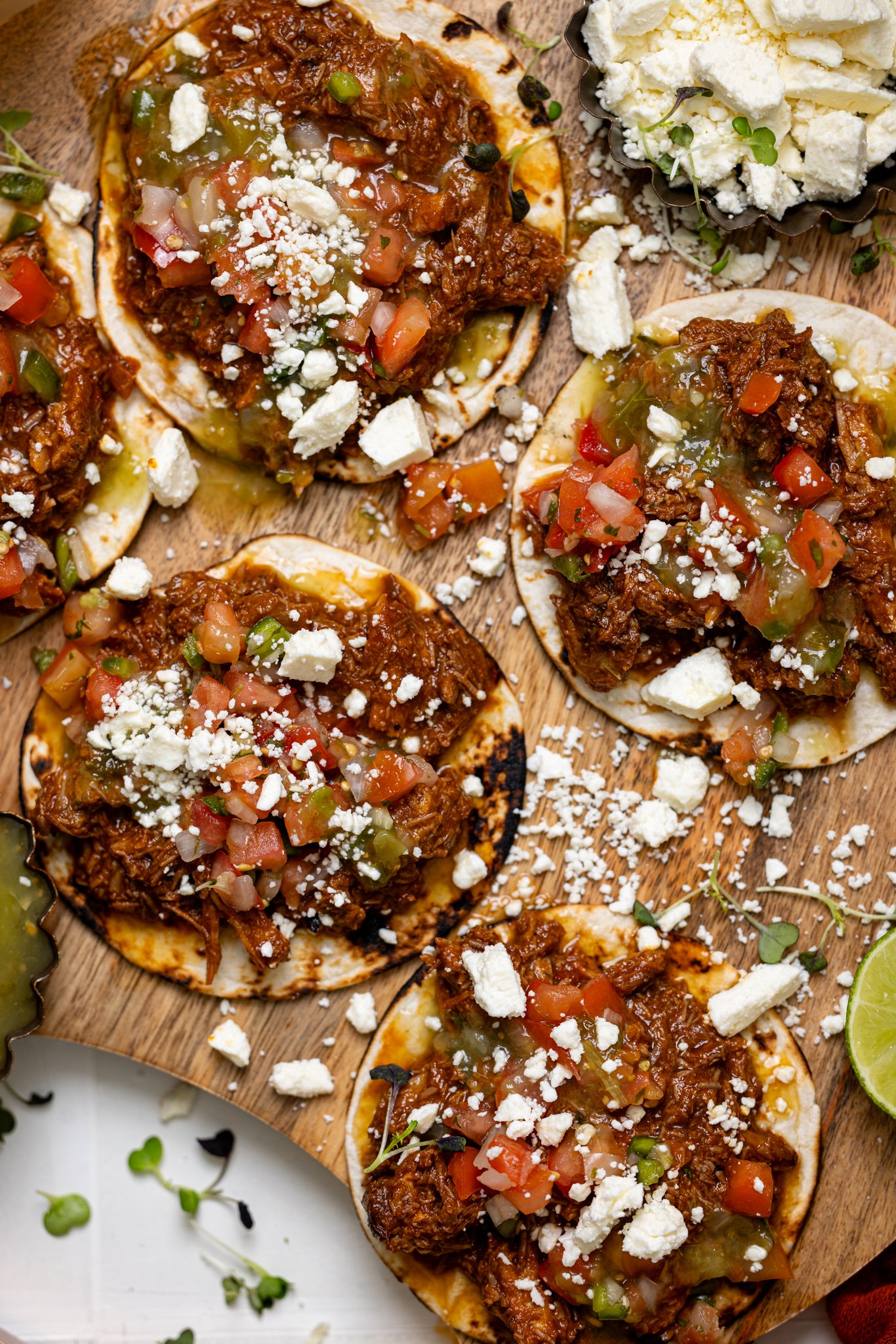 Overhead shot of BBQ Braised Rib Street Tacos on a wooden board with garnish.