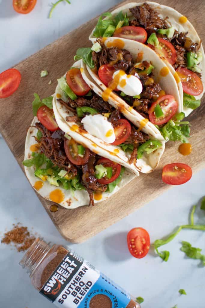 Sweet Heat Barbeque Braised Rib Tacos surrounded by halved tomatoes.