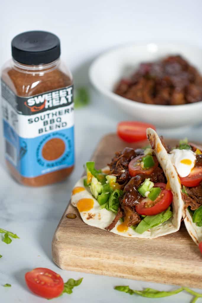 Sweet Heat Barbeque Braised Rib Tacos next to a jar of Sweeet Heat Southern BBQ Blend seasoning.