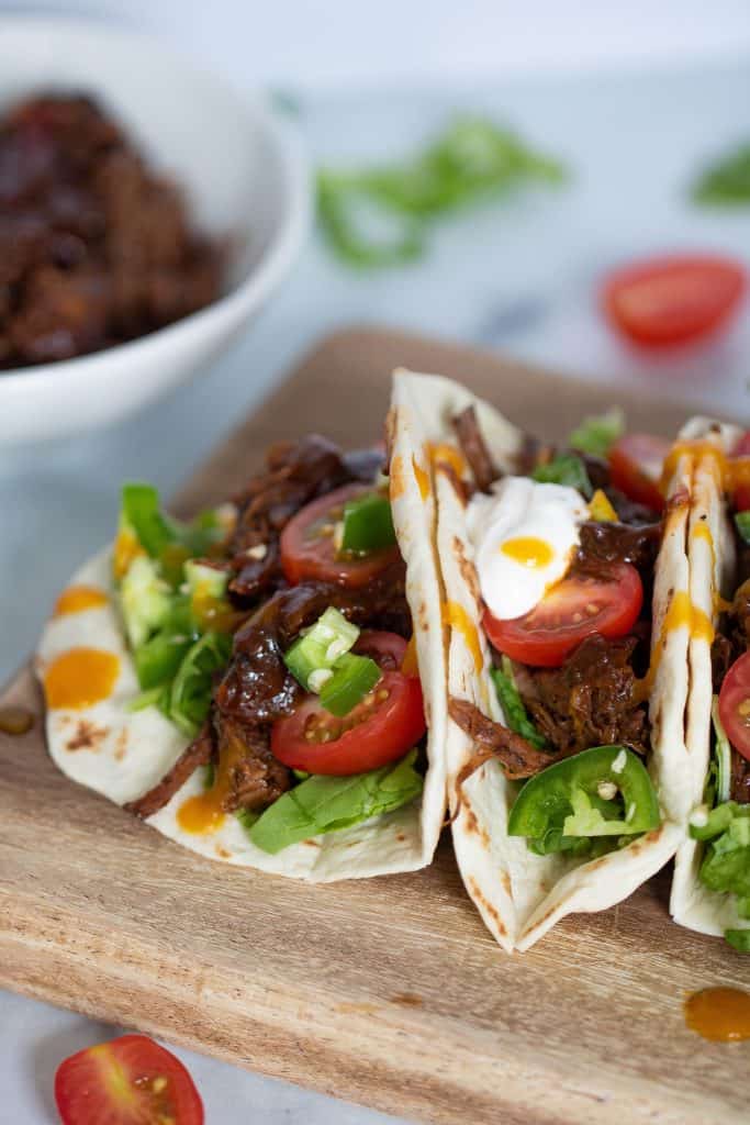 Sweet Heat barbeque Braised Rib Tacos leaning against each other on a board.