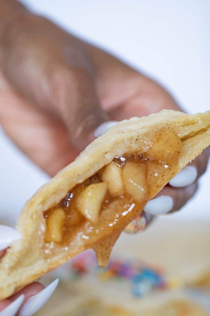 Woman holding a Vegan Apple-Cinnamon Pop Tart with filling falling out.