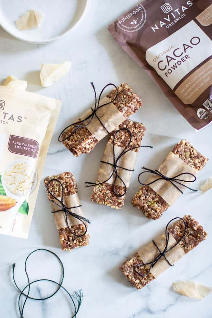 No-Bake Cacao Date Loaded Energy Bars with bags of Navitas cacao powder and cacao butter.