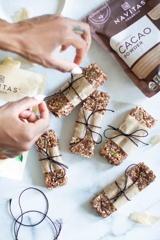 Woman tying twine around a No-Bake Cacao Date Loaded Energy Bar.