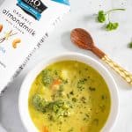 Overhead shot of Loaded Dairy-Free Broccoli Cheddar Soup next to So Delicious almond milk.