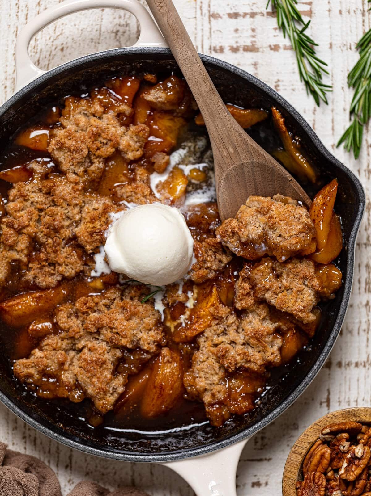 Wooden spoon scooping Vegan Southern Peach Cobbler.