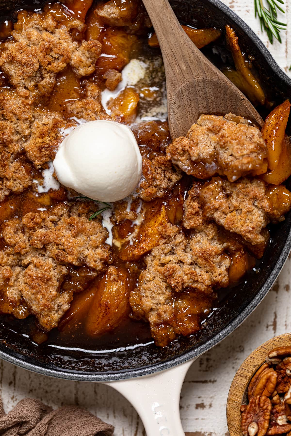 Wooden spoon scooping Vegan Southern Peach Cobbler from a skillet.