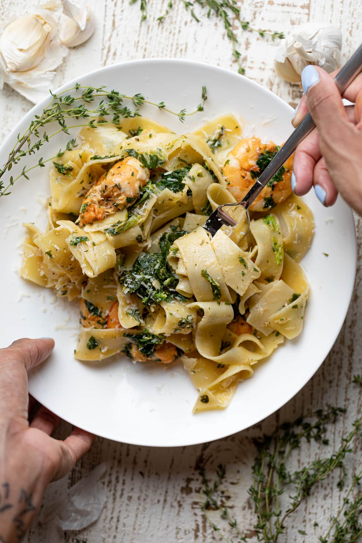 Woman grabbing Savory Lemon Garlic Shrimp Pasta with a fork.