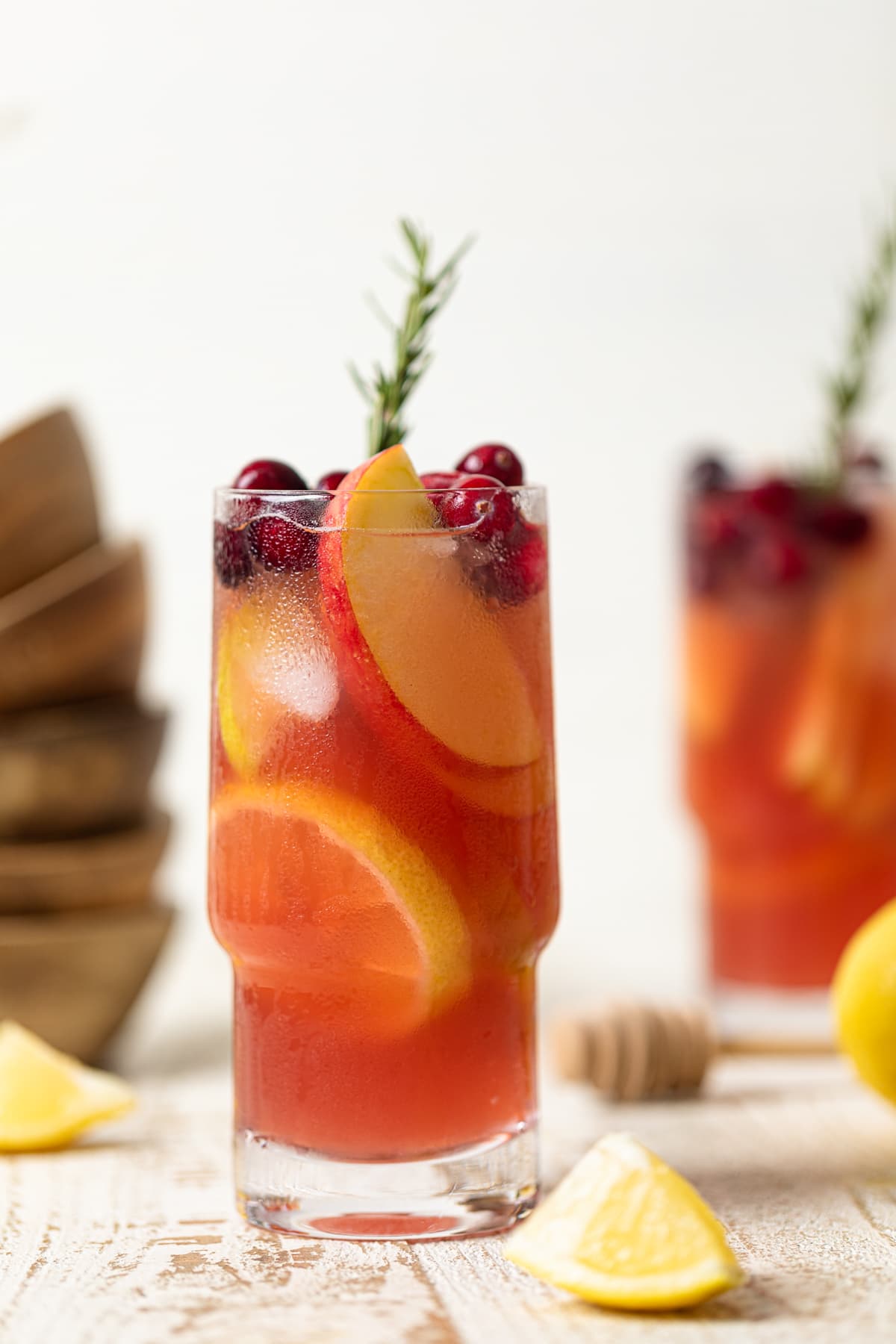 Tall glasses of Apple Cranberry Ginger Lemon Detox Juice on a table with lemons.