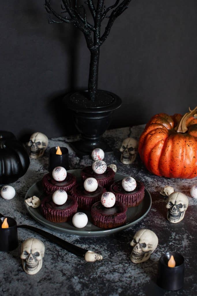 Plate of Halloween Graveyard Cheesecake Bites on a Halloween decorated table.